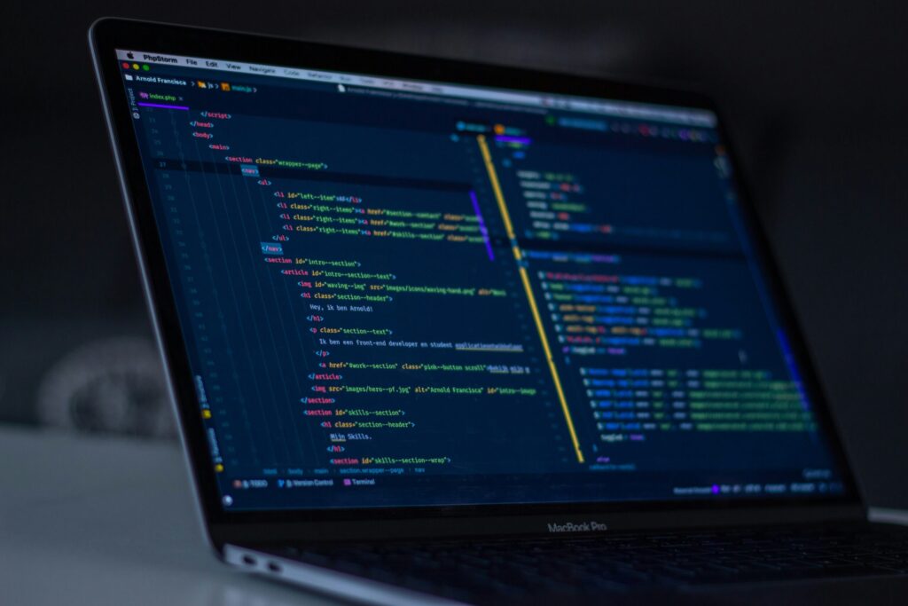 Laptop screen displaying HTML and CSS programming code on a developer desk, web development concepts.